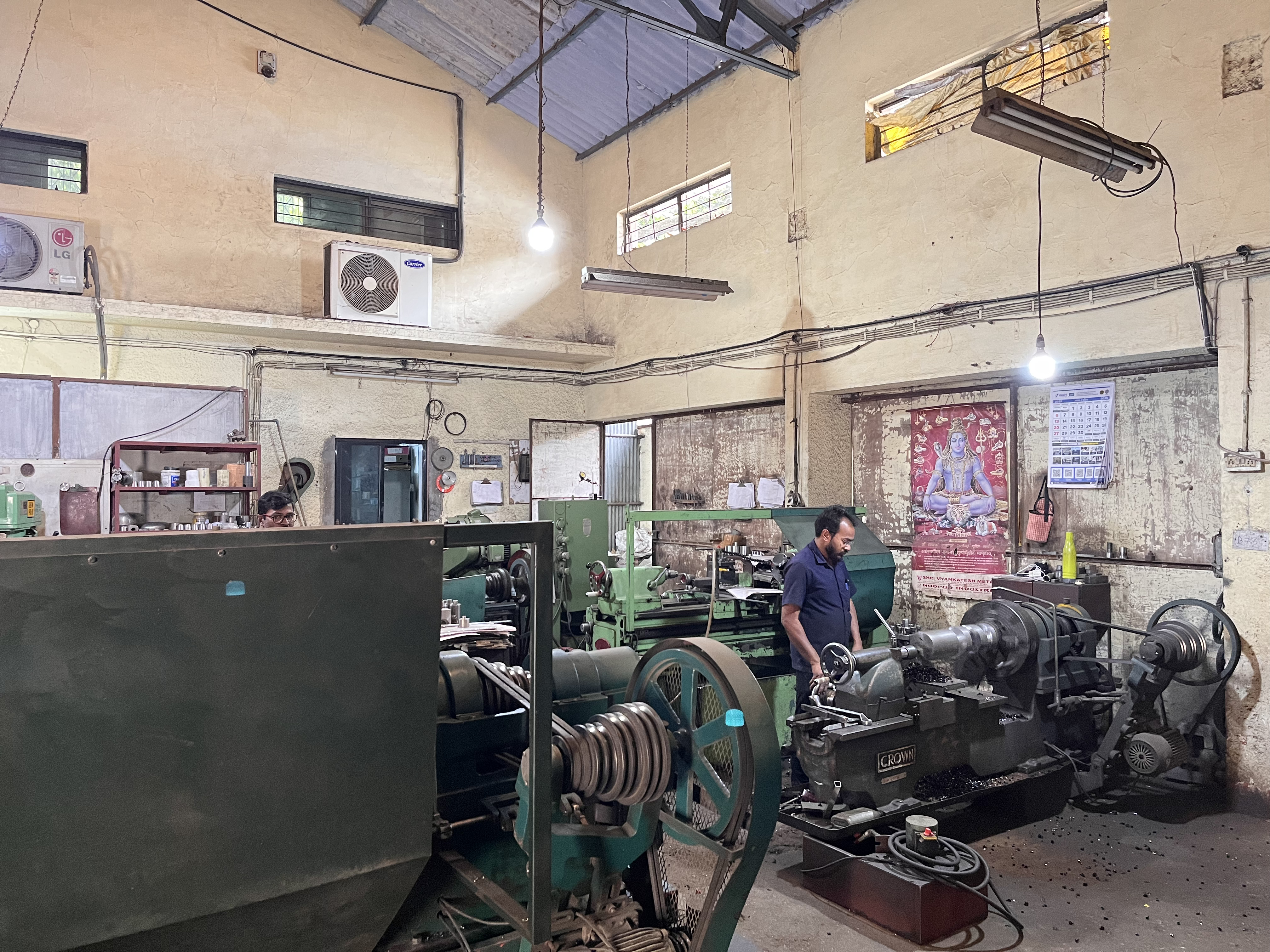 Alen Baby standing in the family manufacturing workshop with industrial lathes and machinery
